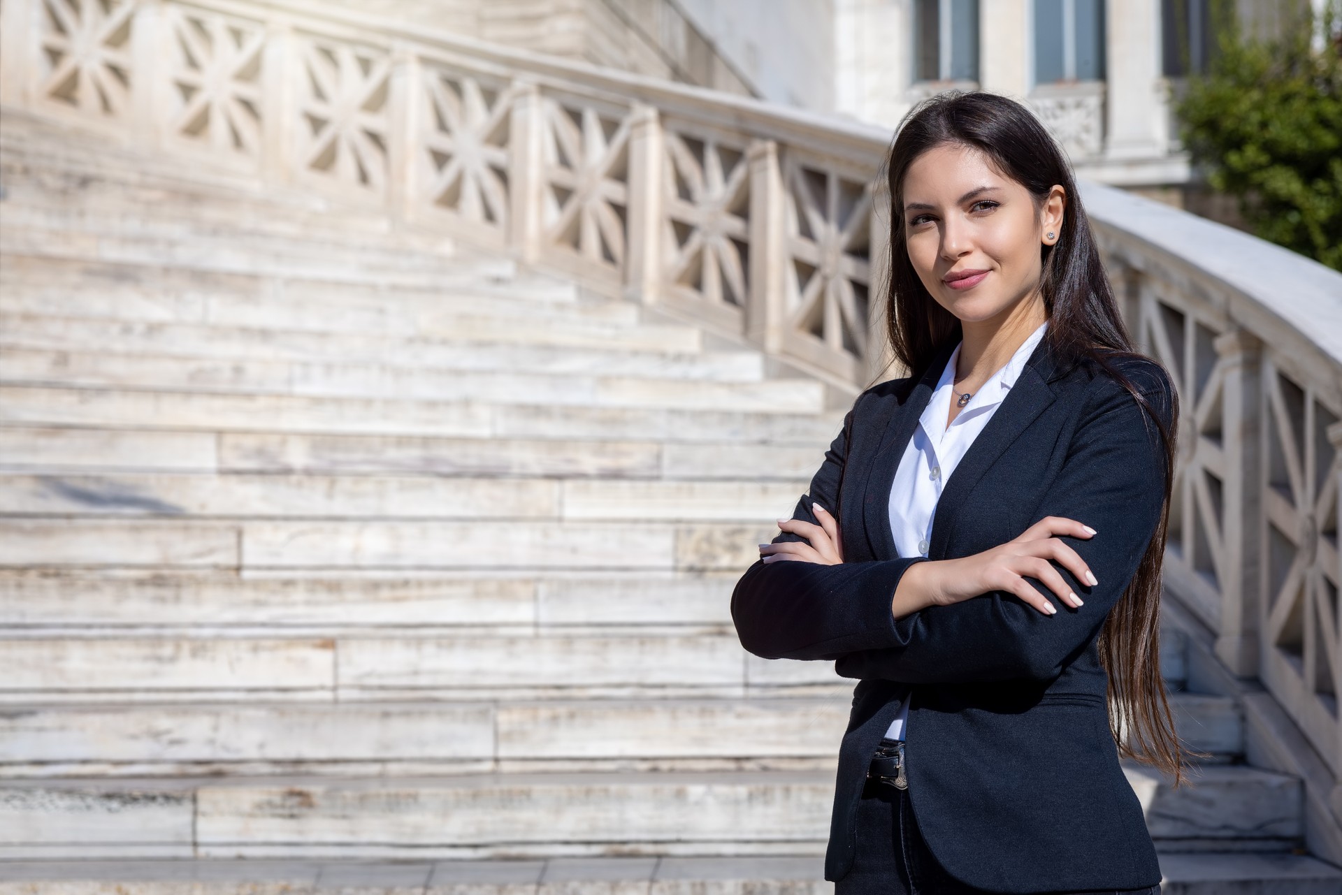 Portrait of a confident buisness woman with crossed arms standing in front at a staircase